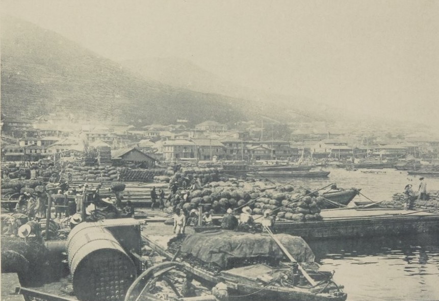 1897年ごろの函館港の古写真。岸に荷を積んだ船が並び、背後に函館山がそびえる