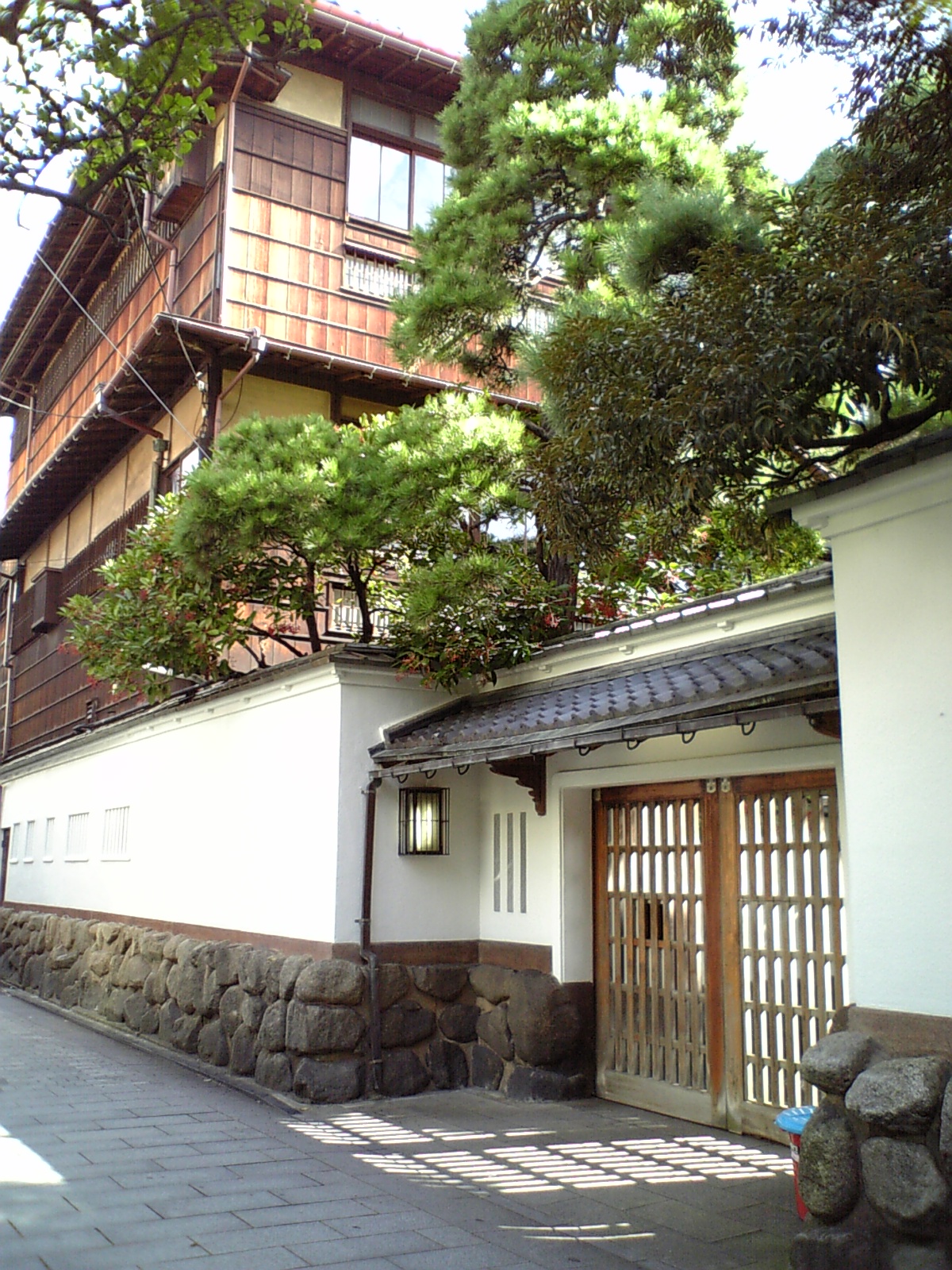 白壁と門、その奥に木造3階建ての建物が見える鍋茶屋の外観