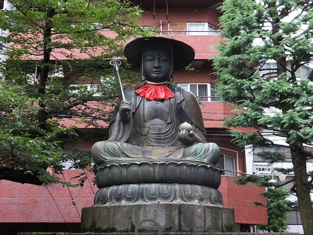 新宿・太宗寺の境内に座る銅造の地蔵菩薩坐像と、周囲のビル