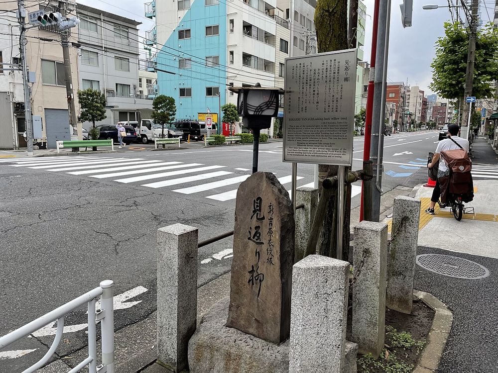 交差点の角に立つ「見返り柳」と刻まれた石碑と説明板