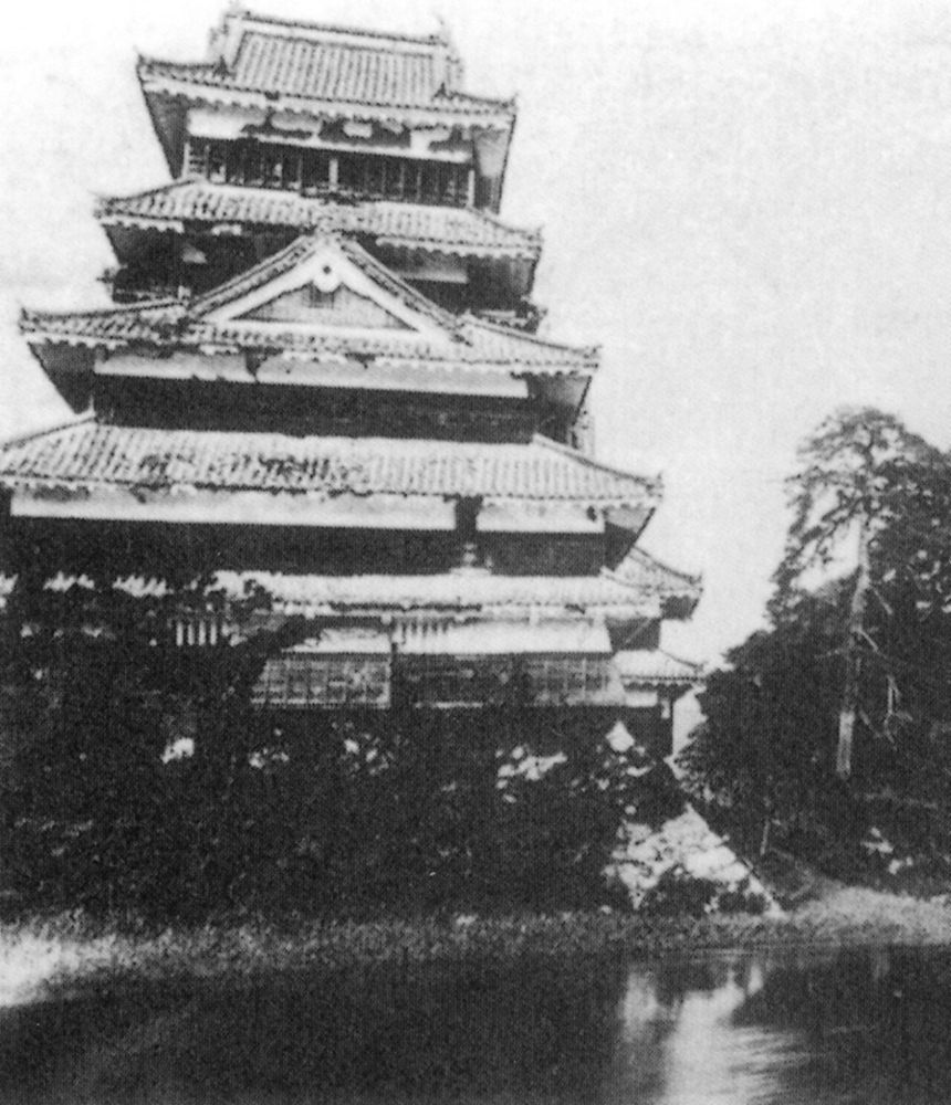 明治時代に撮影された松本城天守の古写真。堀の水面の向こうに、屋根を重ねた天守がそびえる