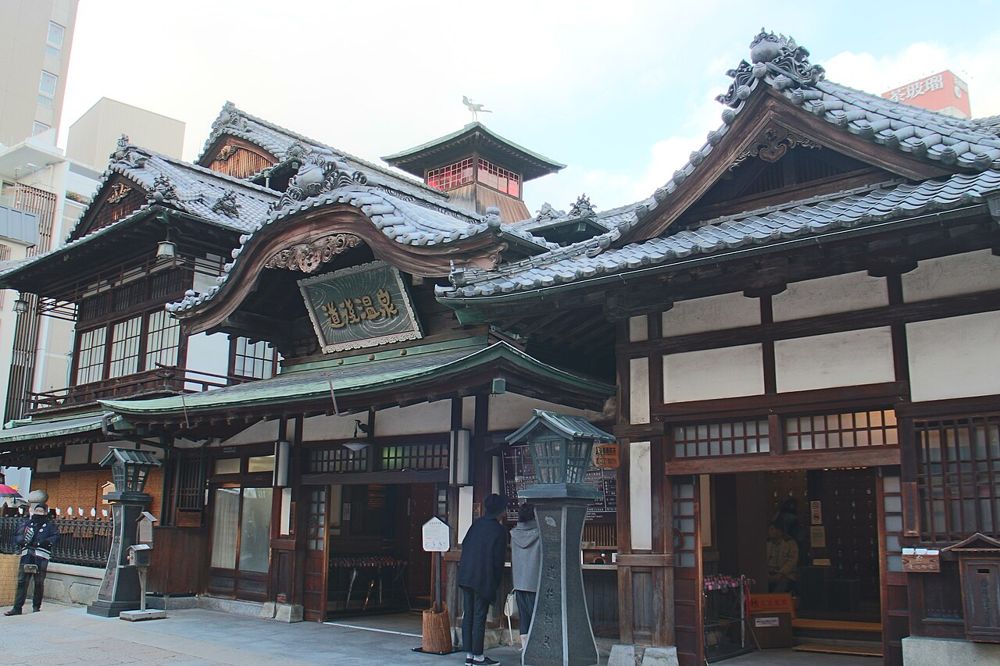 道後温泉本館の外観。木造の入母屋造りの建物で、屋根の上に振鷺閣がのる
