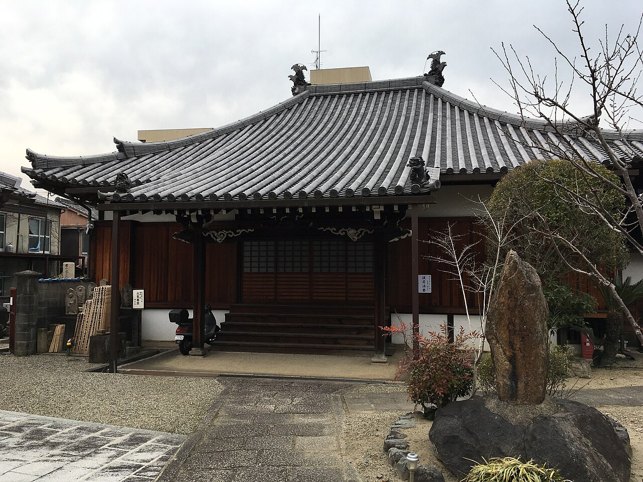 称念寺の本堂。瓦屋根の建物の前に石碑が立っている